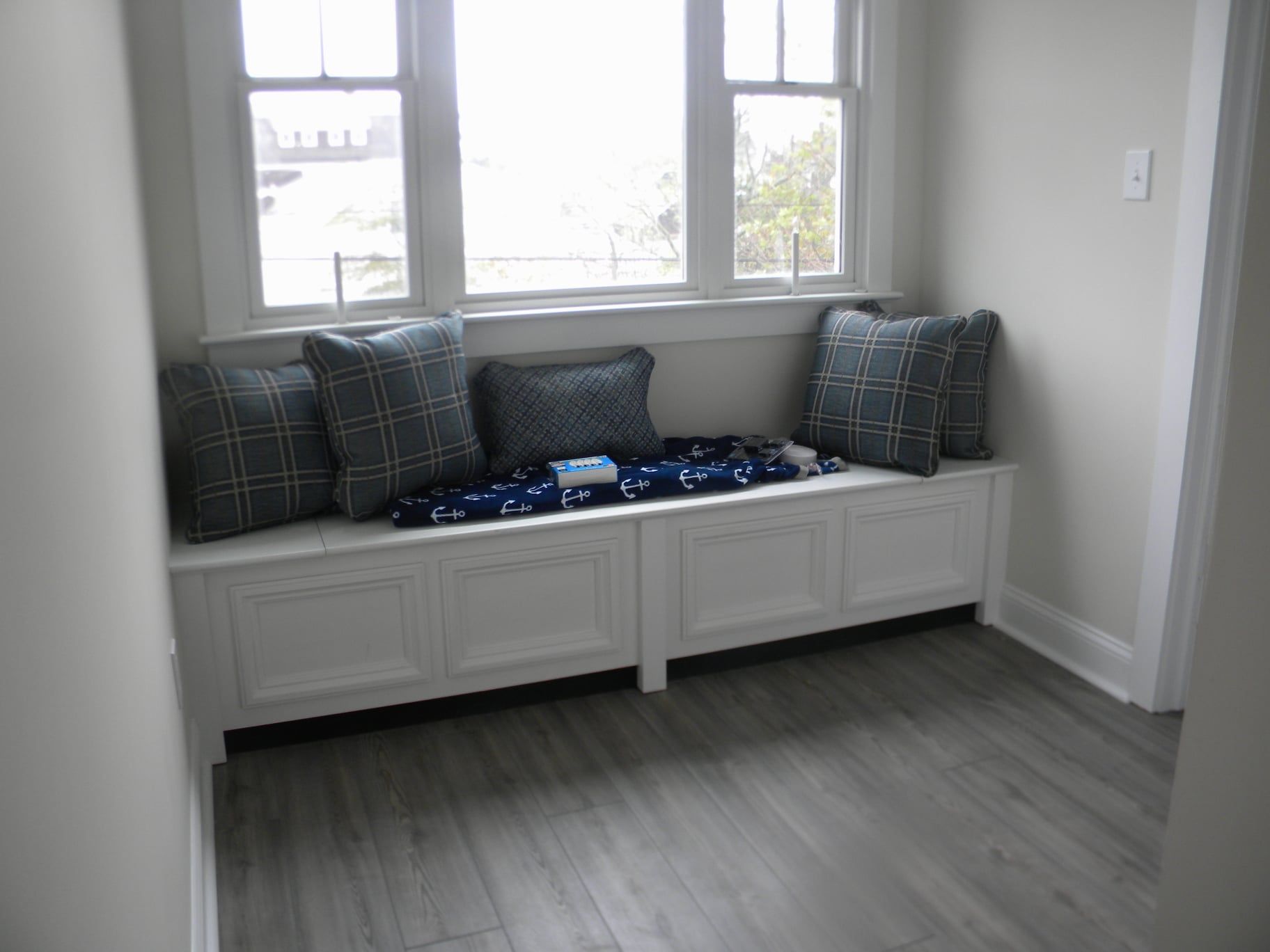 a custom built bay window seat with pillows and a blanket on it