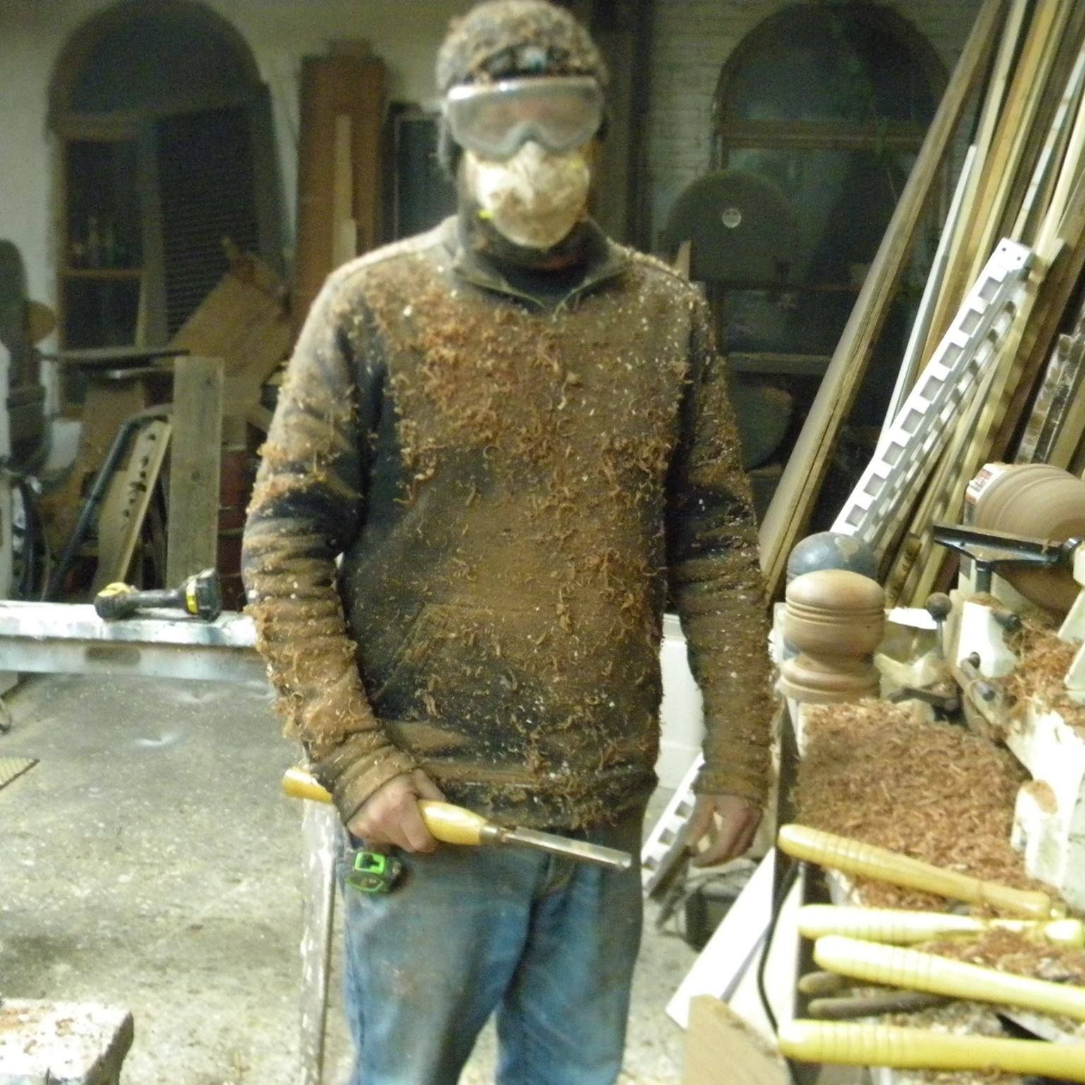 a man covered in wood dust wearing a mask and goggles is holding a screwdriver