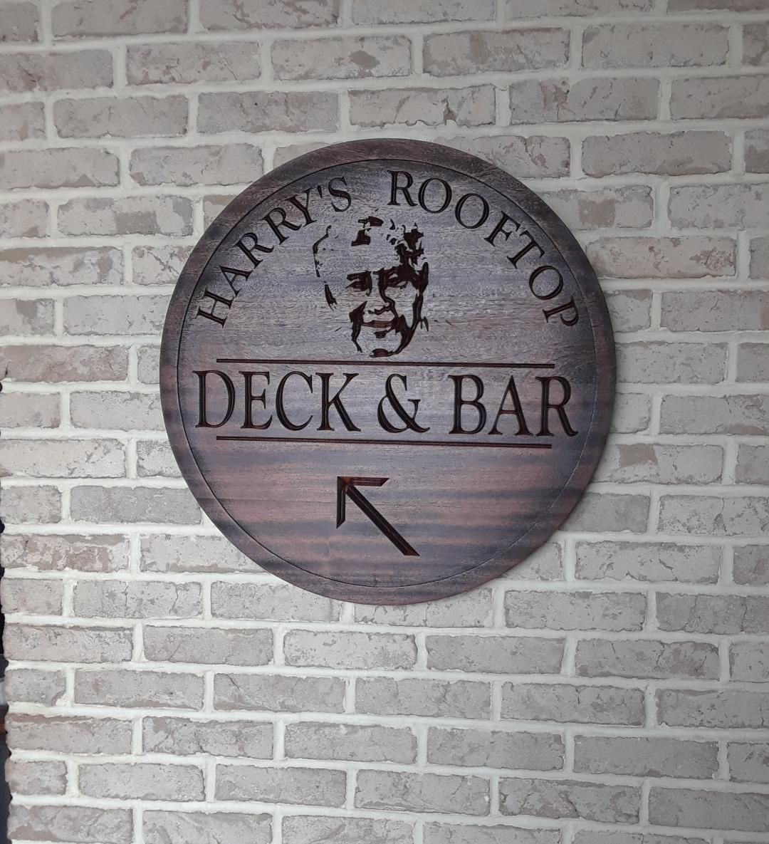 a sign on a brick wall says harry's rooftop deck & bar