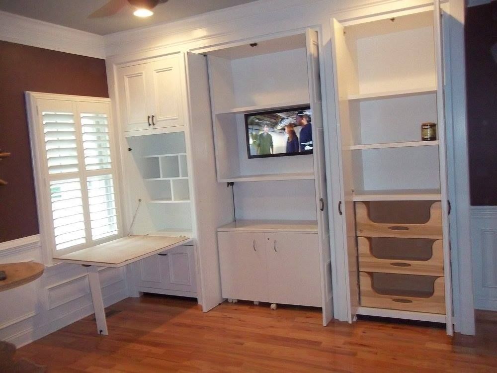 a room with lots of custom built-in shelves and a flat screen tv in it