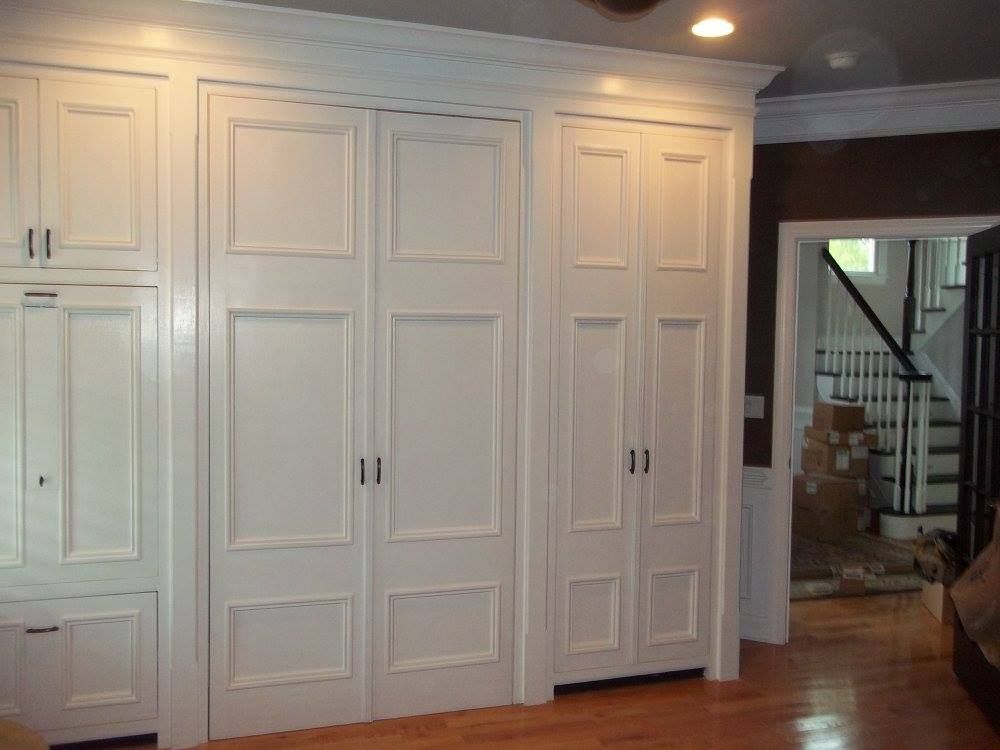 a room with custom built-in white cabinets and a staircase in the background