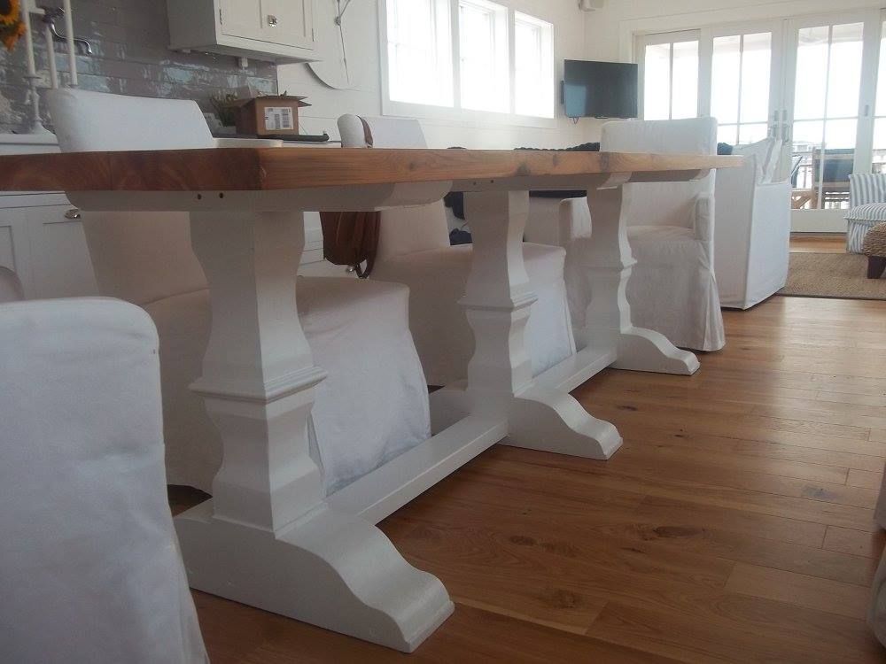 a custom built wooden table with white chairs in a living room