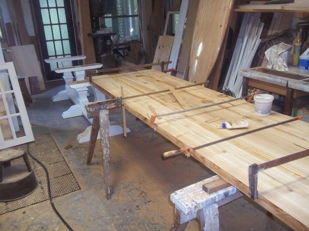 a custom built wooden table is being glued together in a workshop