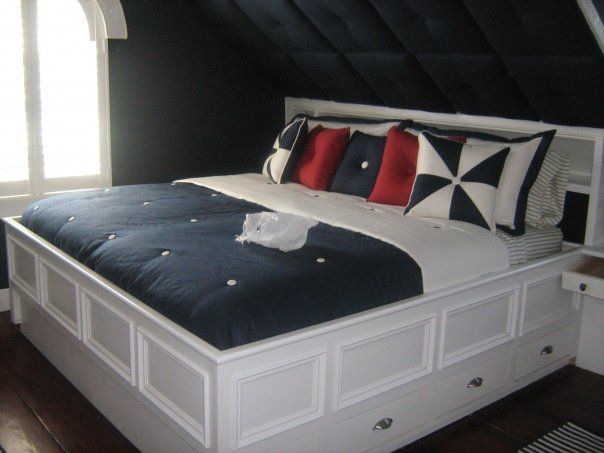 a custom built wooden bed with a blue and white comforter and pillows