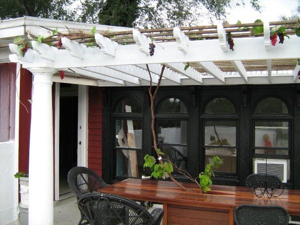 a patio with a custom built wood table and chairs under a pergola