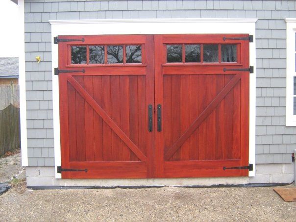 a pair of custom built red wooden garage doors on a gray house