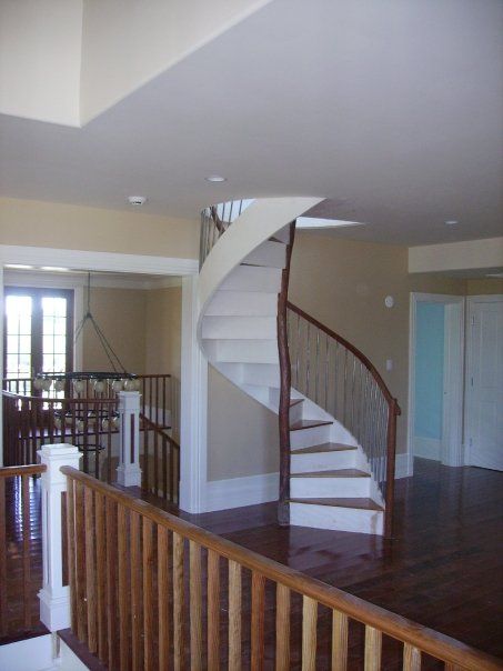 a custom built wood spiral staircase in a house with a wooden railing