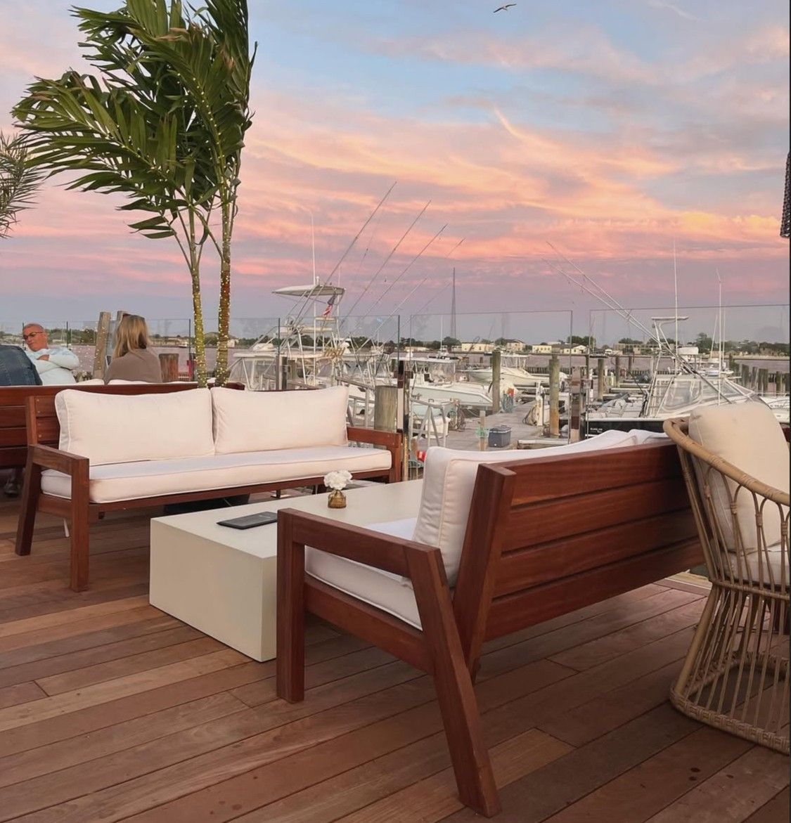 A wooden deck with a couch, chairs, and a table