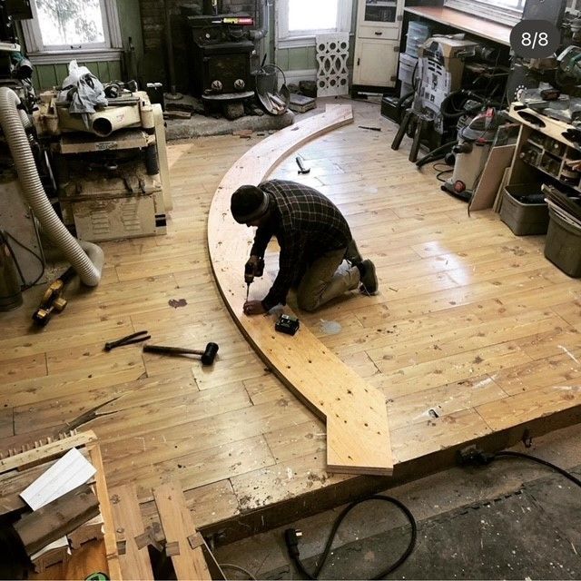 a man is working on a curved piece of wood inside the cape island woodworks workshop 