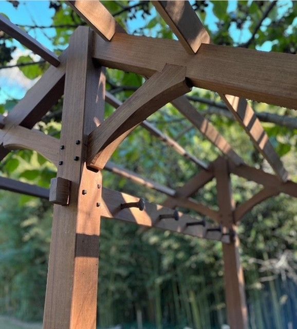 a close up of a wooden pergola structure with trees in the background