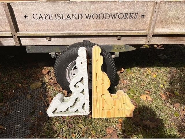 two wooden brackets are sitting in front of a trailer that says cape island woodworks