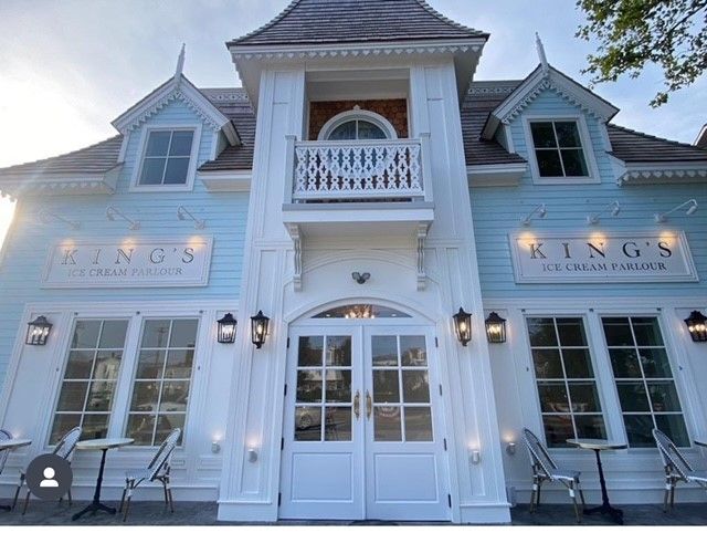 the front of a blue and white building that says kings ice cream parlor with tables and chairs in front of it
