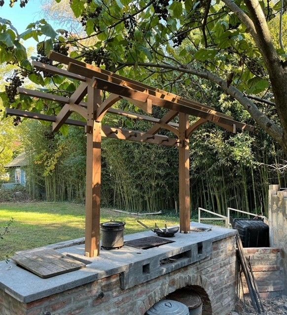 a wooden pergola is sitting on top of an outdoor brick oven and stove top