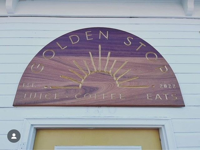a wooden sign that says golden stop coffee shop on the side of a building 