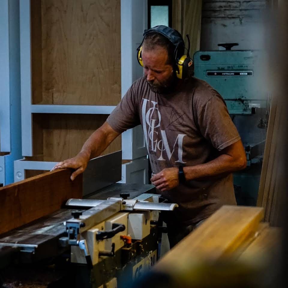 a man wearing headphones is working on a machine with the letter m on his shirt