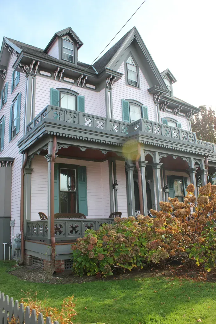 a pink victorian house with blue shutters and a porch in cape may, new jersey