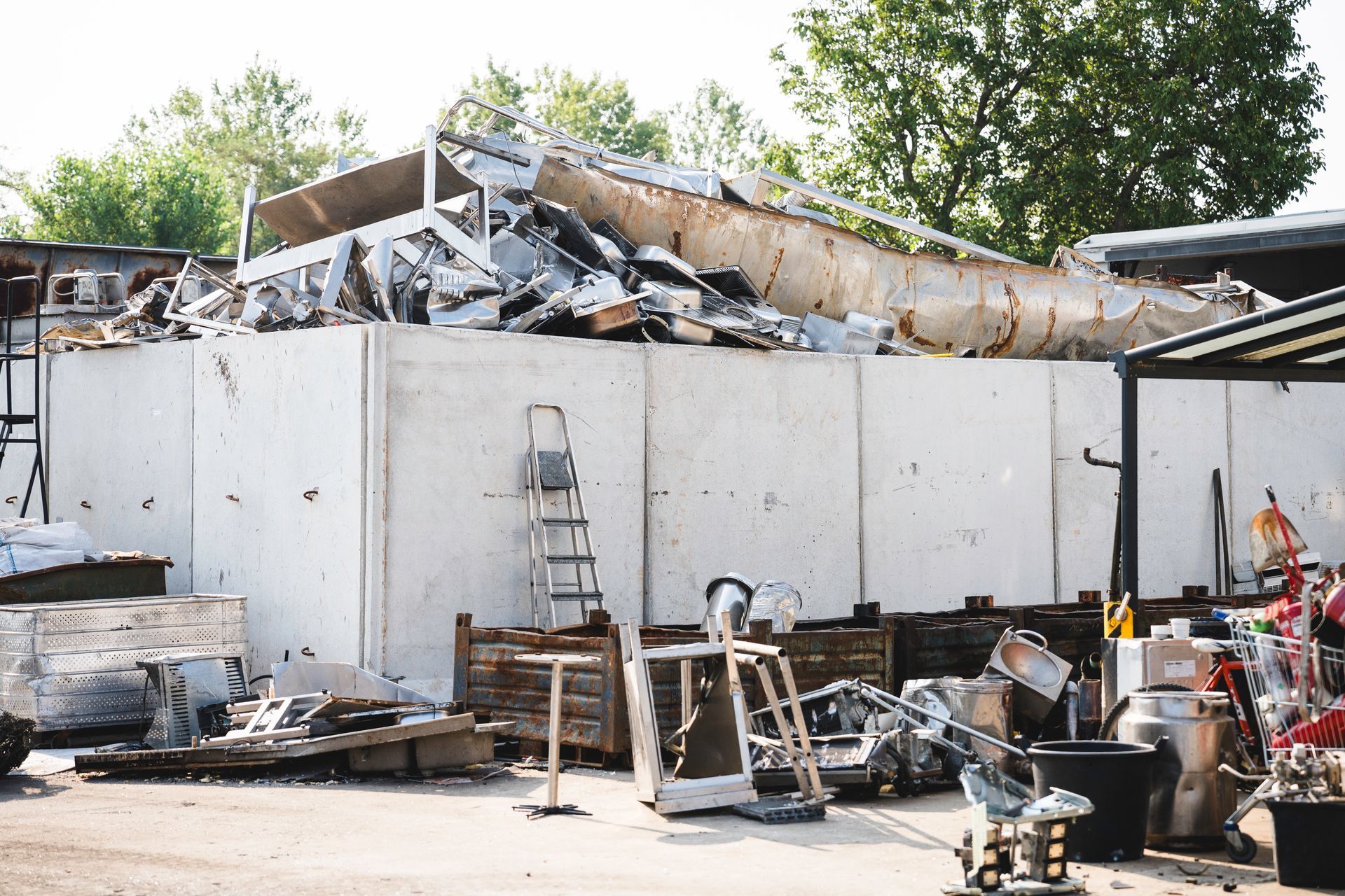 Un cassonetto blu stracolmo di travi di legno rotte e rottami metallici all'aperto.
