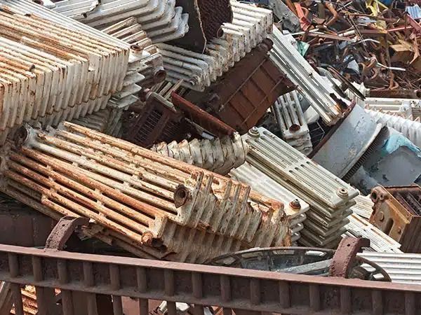 Cumulo di rottami metallici arrugginiti e lamiere ondulate in una discarica.