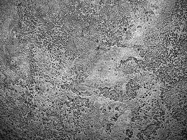 Superficie grigia e ruvida in cemento o pietra, con texture screziata e leggere crepe.