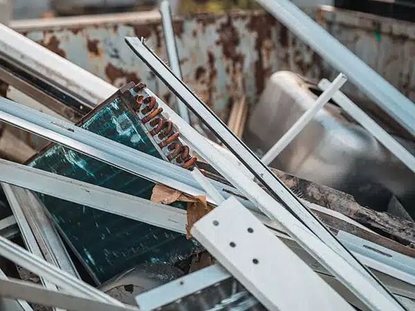 Frammenti di vetro e detriti metallici sono sparsi in una struttura danneggiata, sotto la quale si intravede un circuito stampato color verde acqua.