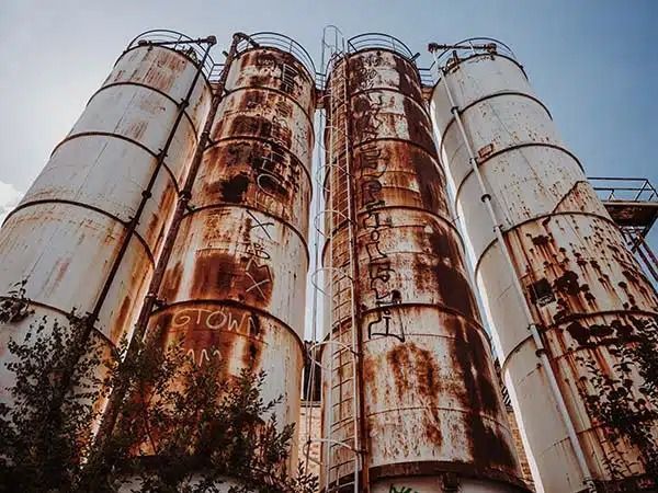 Silos industriali arrugginiti contro un cielo nuvoloso.