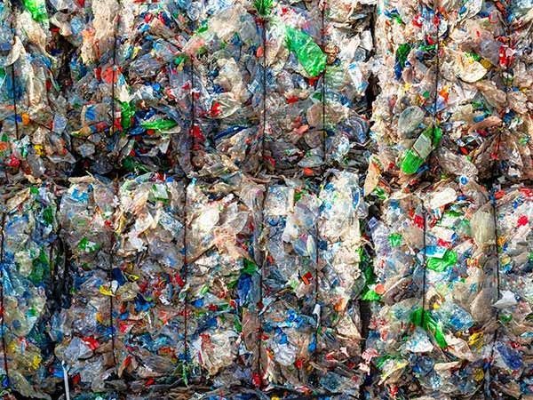Balle di bottiglie di plastica frantumate impilate in file, che mostrano colori e consistenze diverse.