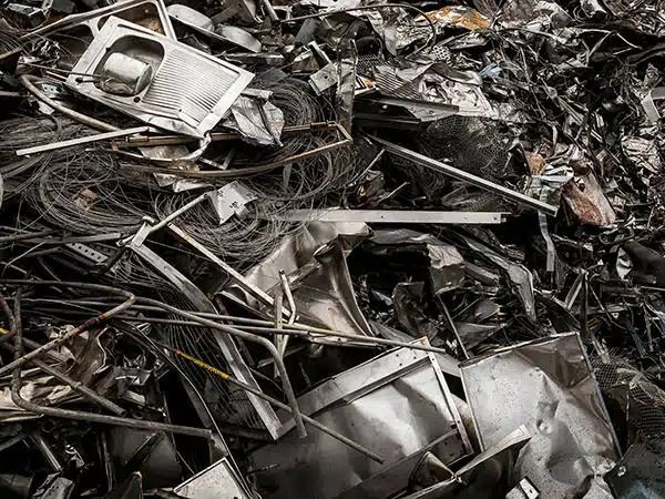 Cumuli di rottami metallici e detriti contorti in una discarica.