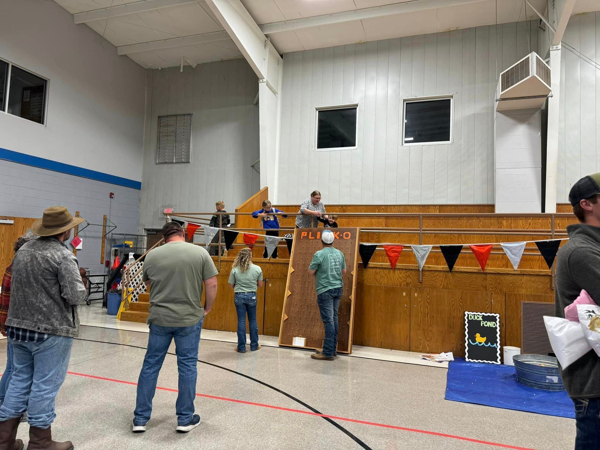 A group of people are standing in a gym watching a game during Octoberfest.