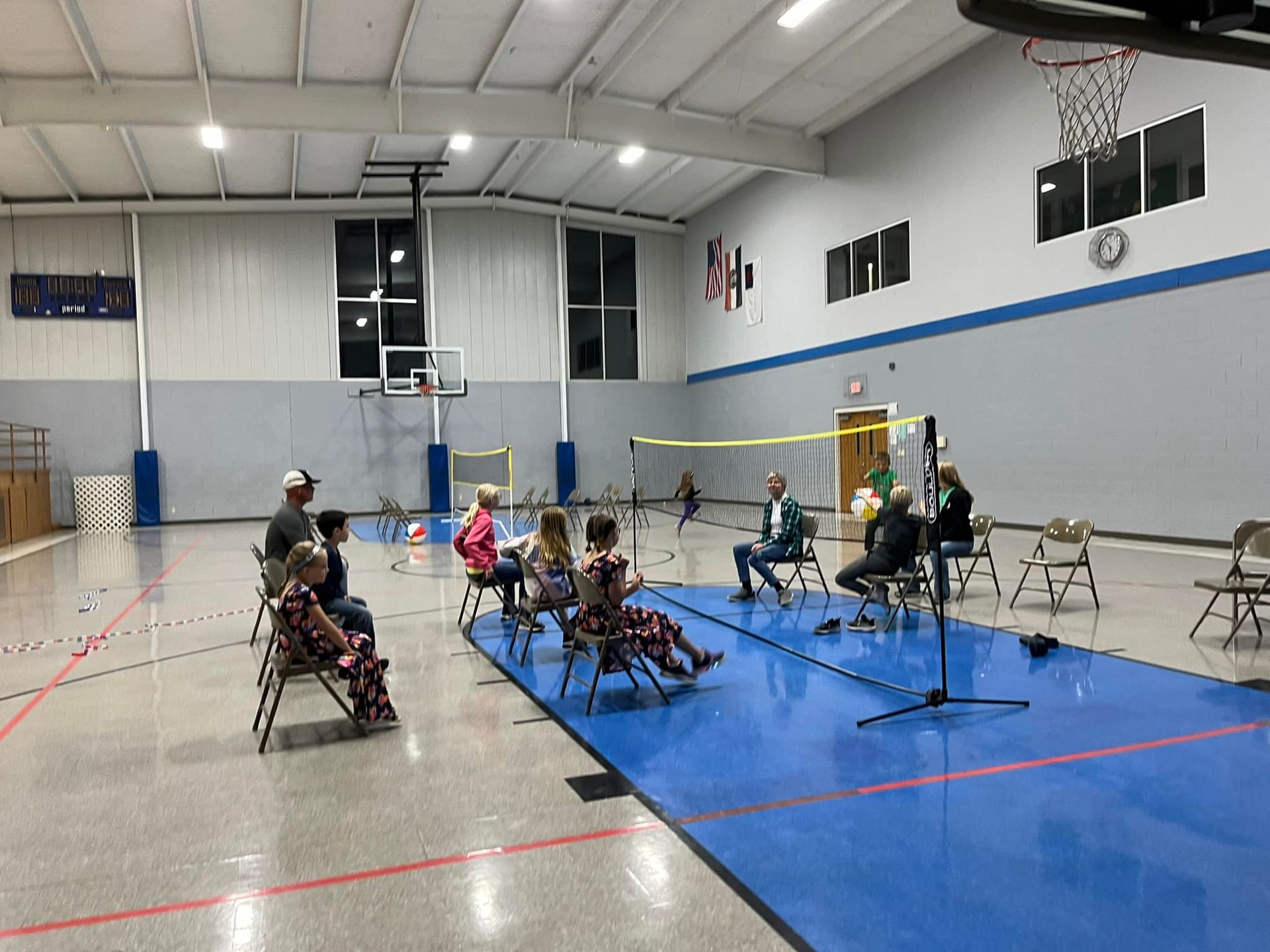 A group of people are playing chair volleyball at a PTL meeting in the gym.