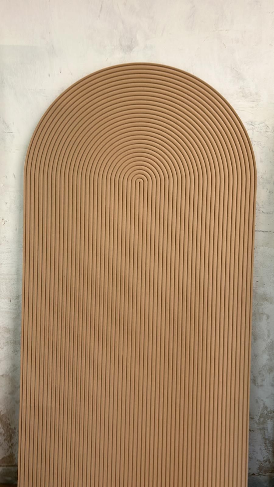 Pannello murale intrecciato color beige arcuato con nervature verticali su una parete chiara