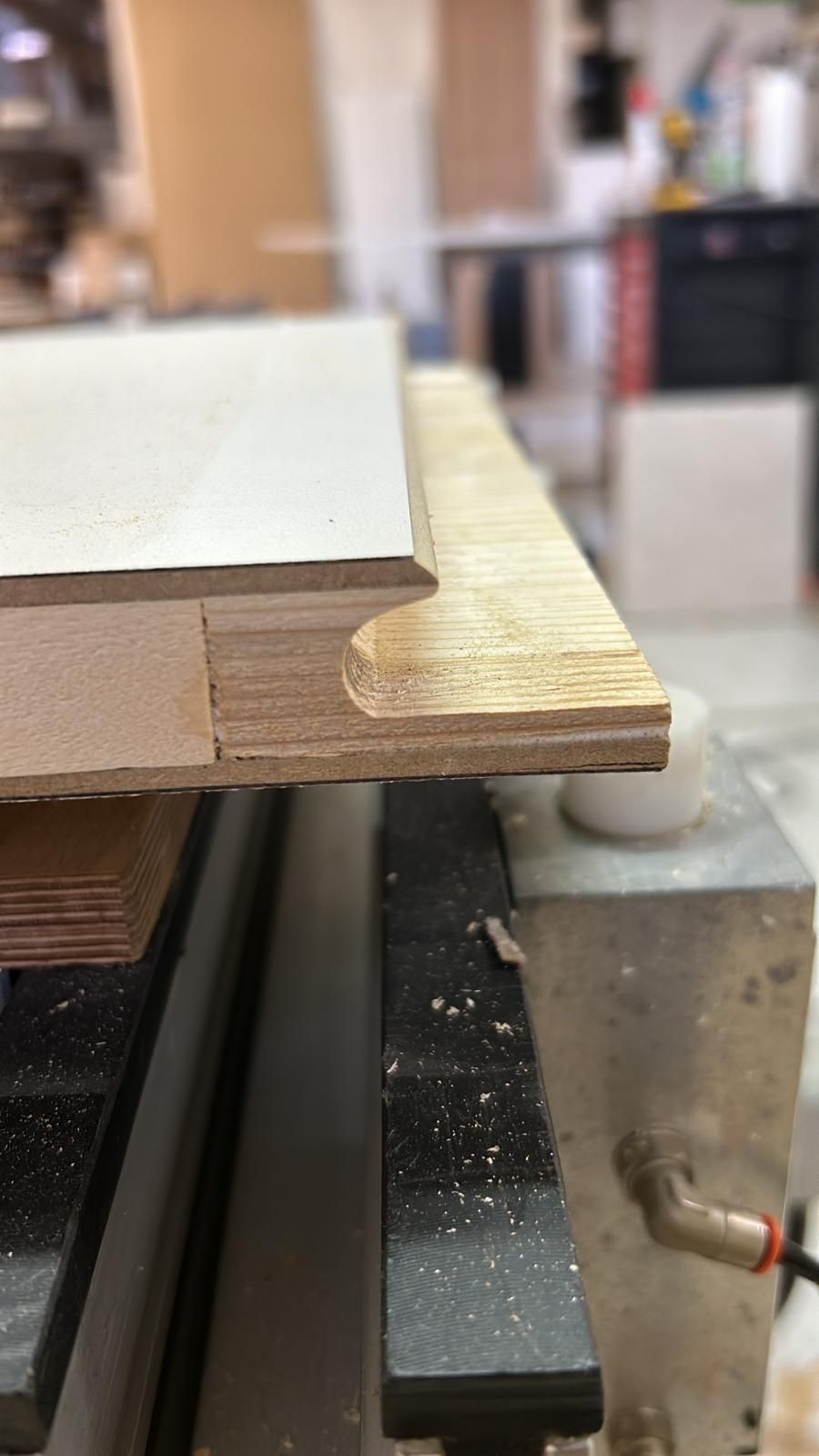 Primo piano di una tavola di legno con un bordo arrotondato su un banco da lavoro in un'officina.