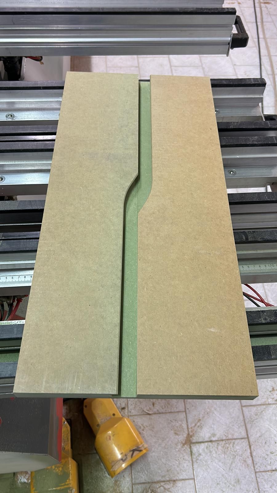 Due pannelli in MDF beige con una scanalatura centrale curva su un banco da lavoro.