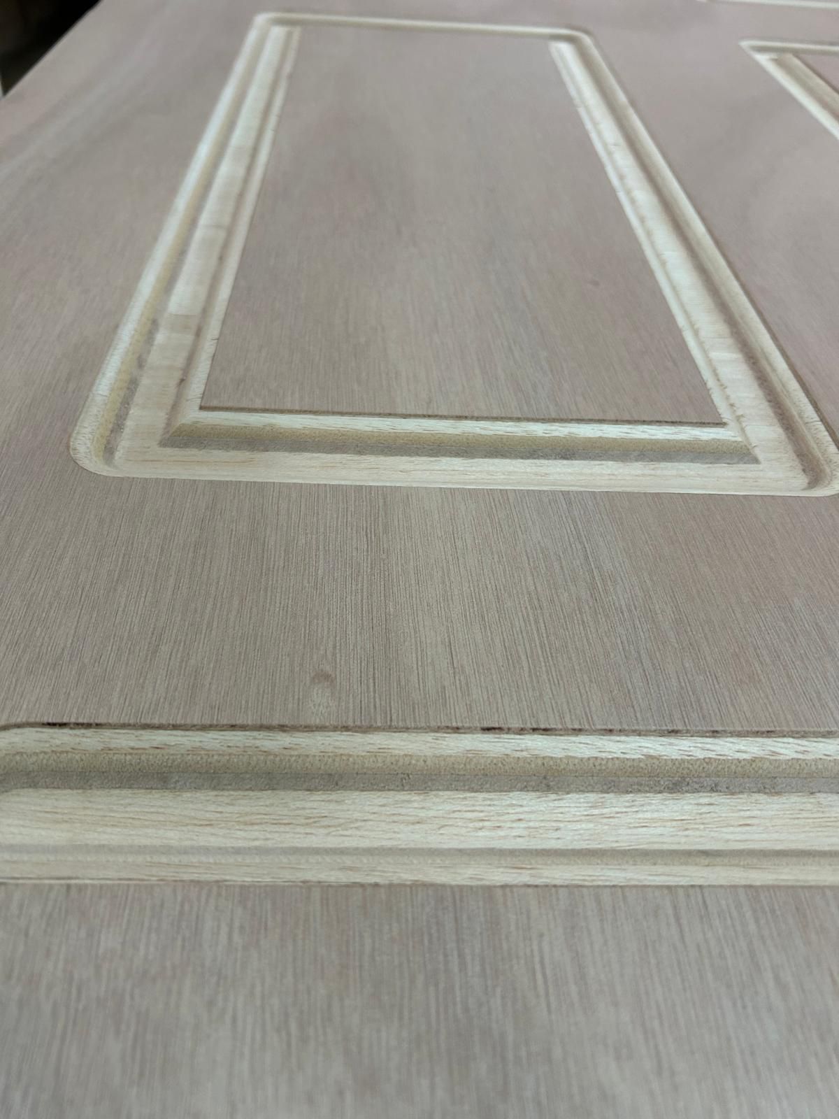 Primo piano di una porta a pannelli beige con modanature in rilievo e cornice bianca.