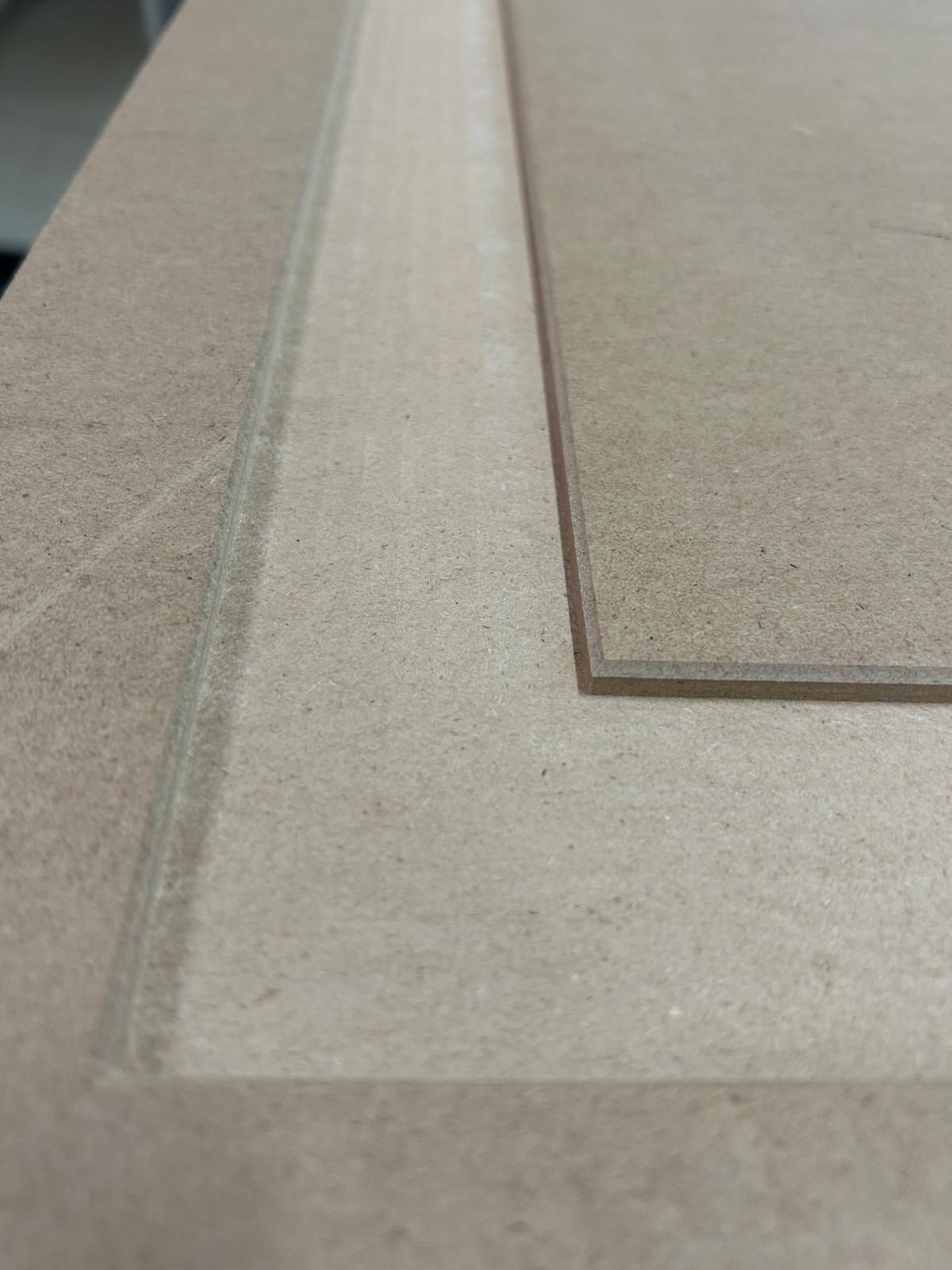 Primo piano di due campioni di moquette beige con un pezzo rettangolare dal bordo scuro che si sovrappone a un angolo.