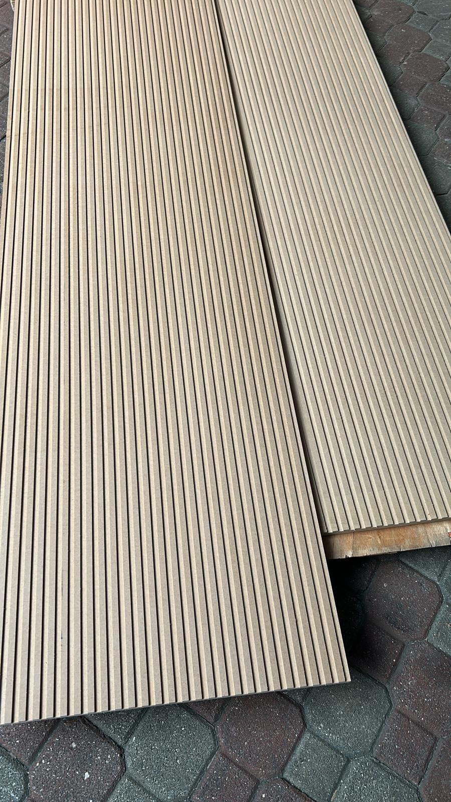 Due pannelli a doghe di legno chiaro appoggiati su una pavimentazione decorata all'aperto