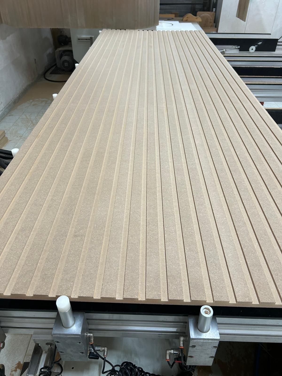 Pannello a doghe di legno su un banco di lavoro, visto dall'alto in un'officina.
