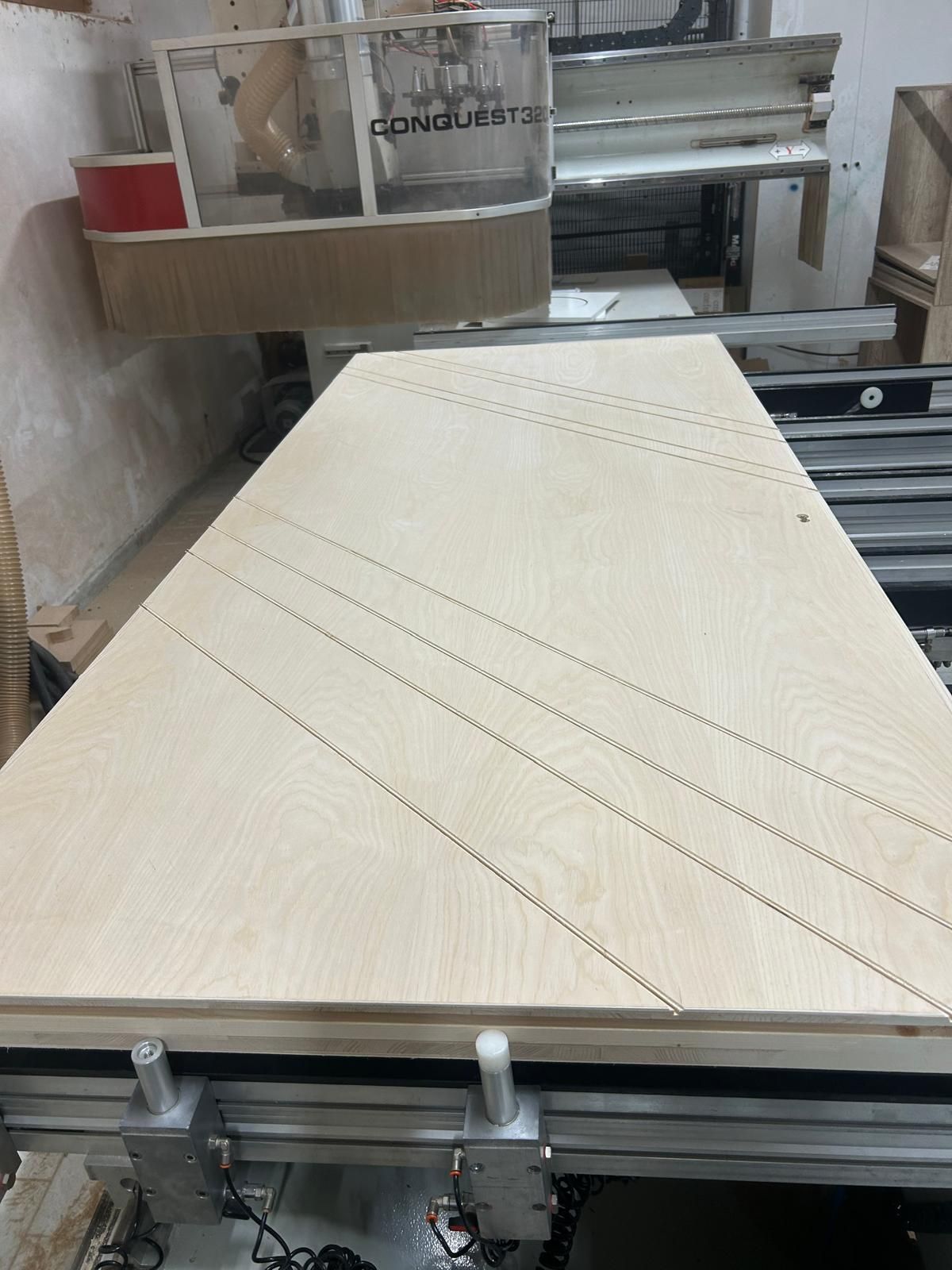 Ampia tavola beige su nastro trasportatore industriale con linee di taglio diagonali in un'officina