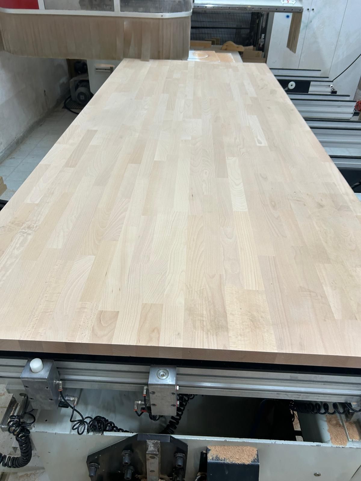 Ampio piano di lavoro in legno chiaro su una macchina per la lavorazione del legno in un'officina.