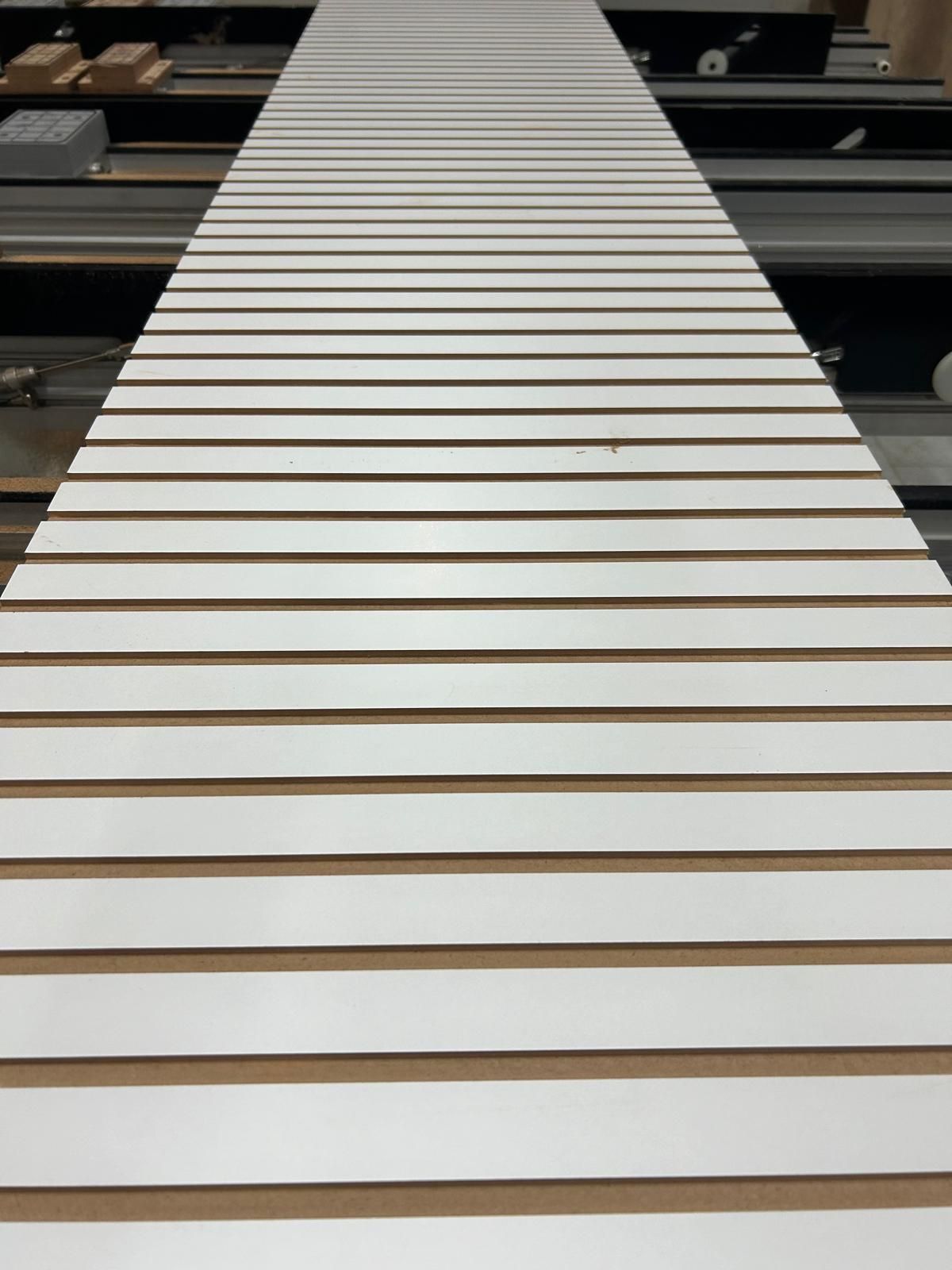 Primo piano di un nastro trasportatore o di un tapis roulant a lamelle bianche che si estende in lontananza.