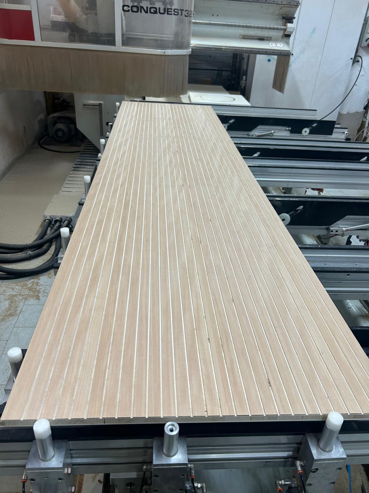 Pannello a doghe di legno sul banco di una macchina CNC in un'officina