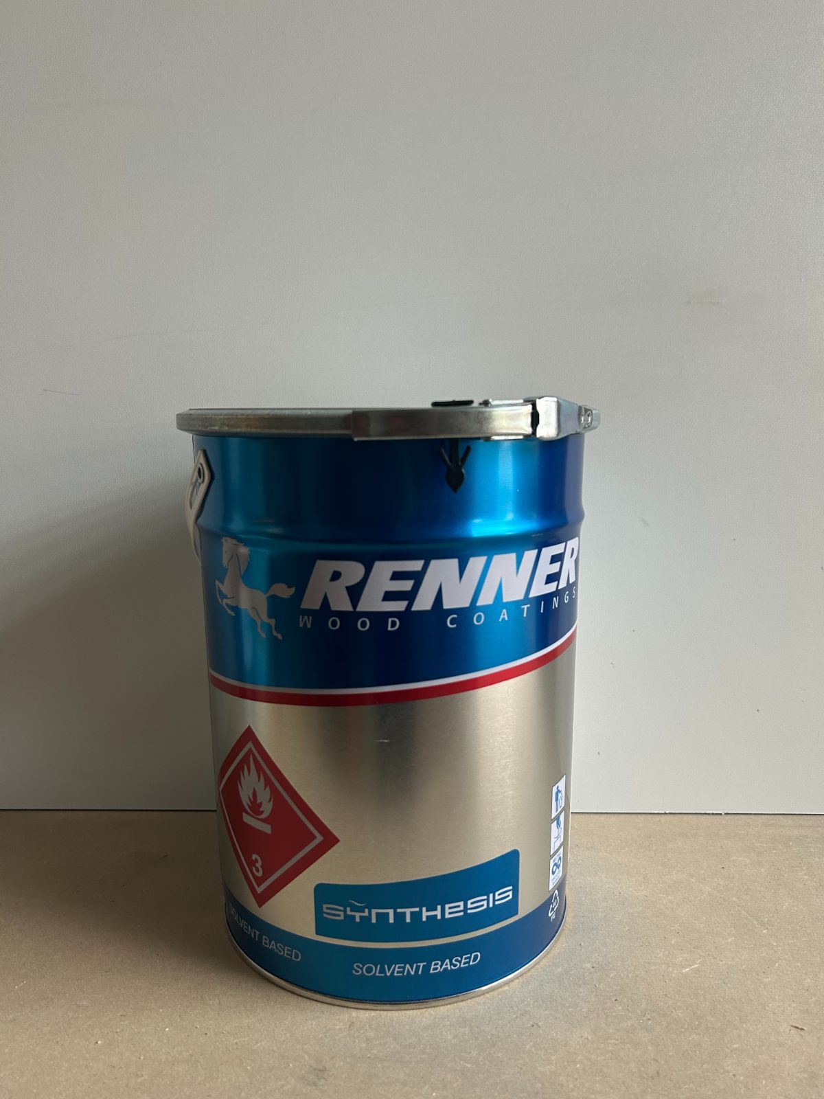 Contenitore metallico blu e argento con etichetta di avvertenza rossa su una superficie liscia.