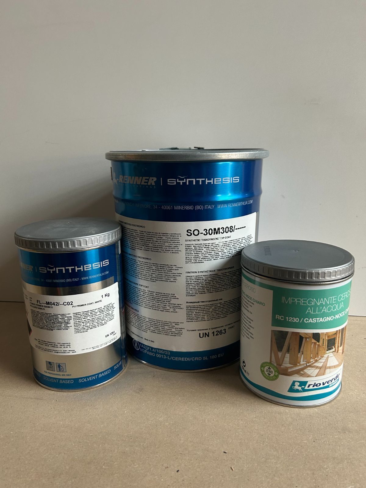 Tre barattoli di vernice assortiti nei colori blu, argento e verde acqua su una superficie piana