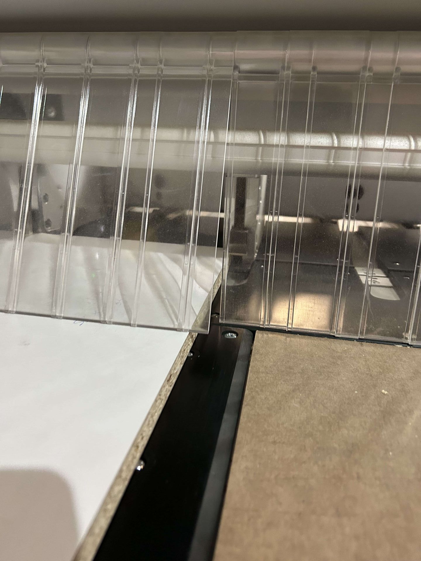 Scolapiatti in metallo argentato con utensili appesi sopra un piano di lavoro bianco con lavello.