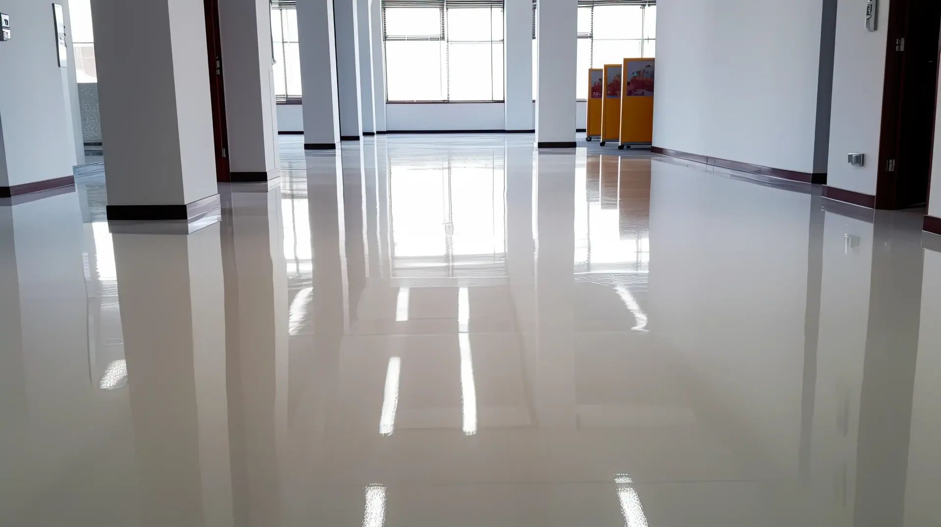 Shiny, tiled floor reflects light in an empty, bright room with white pillars and windows.