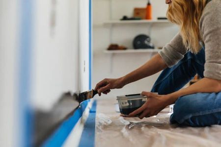 A person is painting a balcony with a roller.