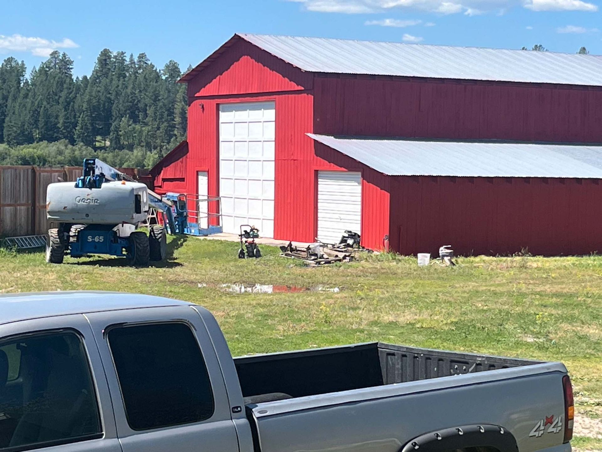 A truck is parked in front of a red barn