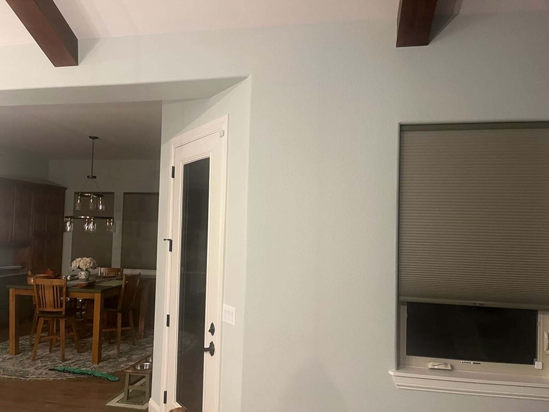 A living room with a dining room table and chairs and a window.