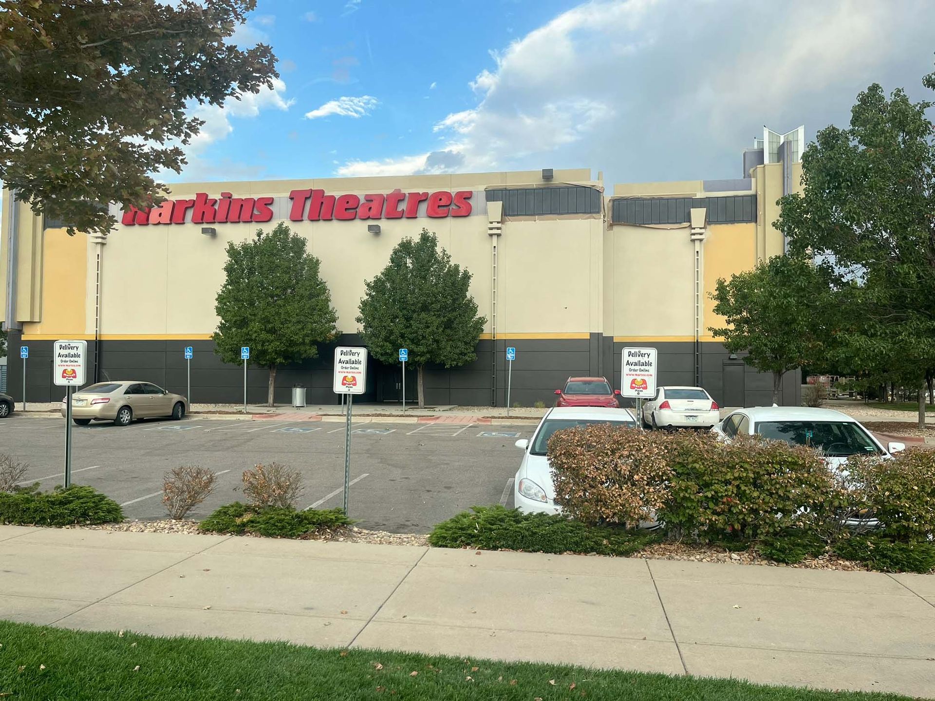 A parking lot with cars parked in front of a theatre