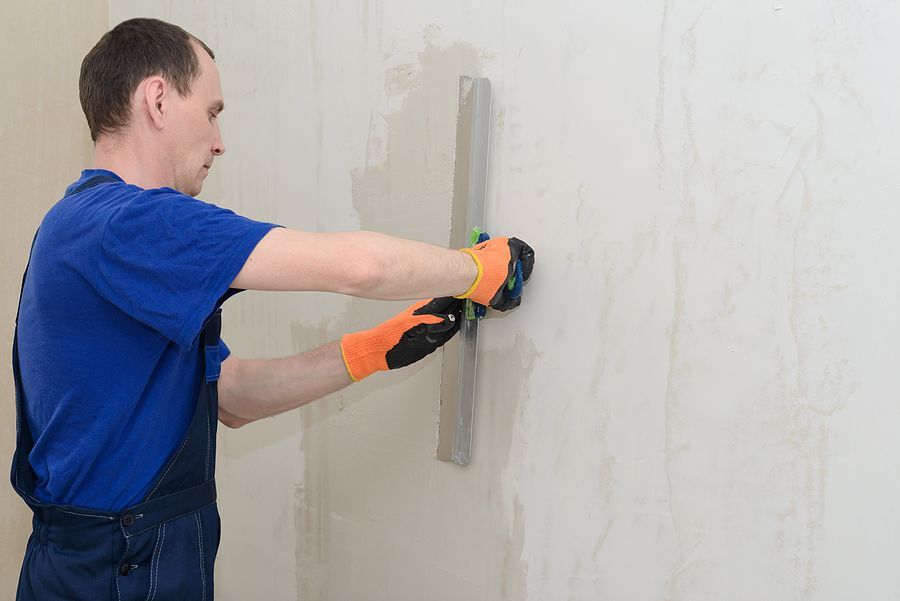 a man in a blue shirt is painting a wall