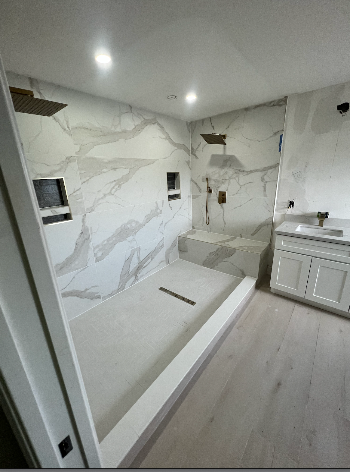 Modern bathroom with marble-tile shower, built-in bench, and vanity cabinets